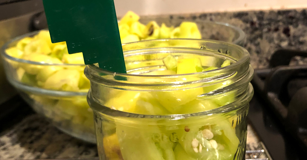 Measuring half inch headspace in jar of banana peppers