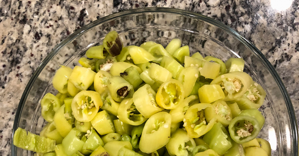 Slices of banana peppers in a clear glass bowl on a counter