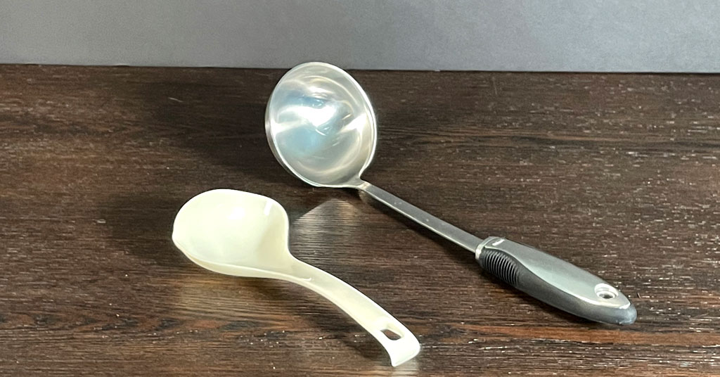 Metal ladle and plastic ladle used for canning sitting on a wooden table