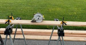 Circular saw sitting on 2x12x12 board propped up on saw horses. Board will be used to build a raised garden bed.