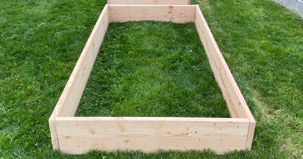 4 foot by 8 foot by 12 inch raised garden bed made out of douglas fir boards sitting on the green grass.