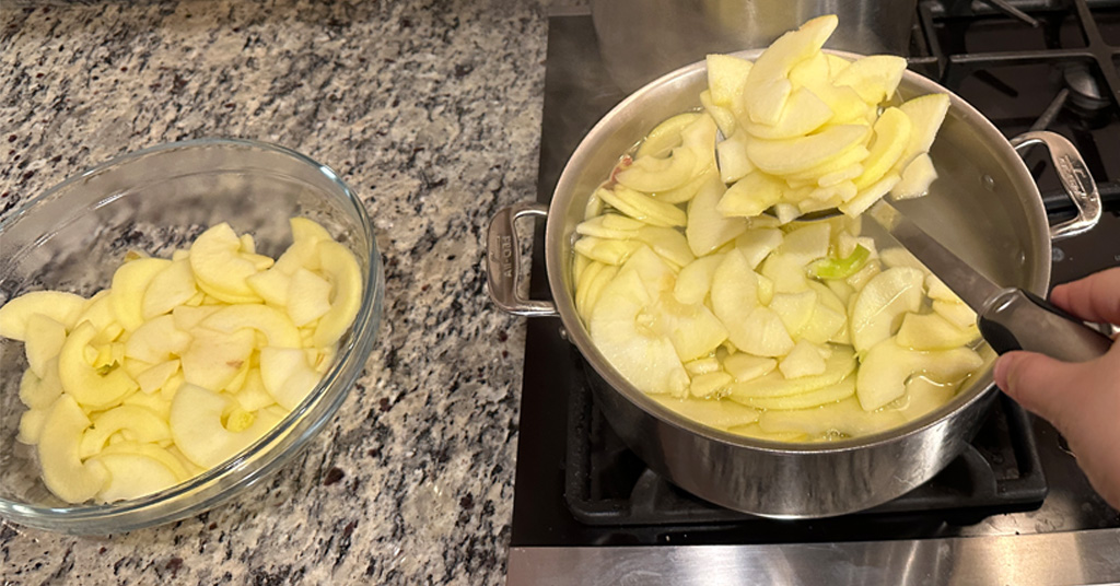 Blanching Apples in a pot of boiling water. Removing apples into a glass bowl when blanching time complete