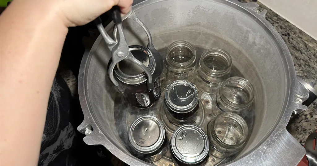 All American Pressure Canner with mason jars. Some mason jars are full of black beans some have not been filled yet.