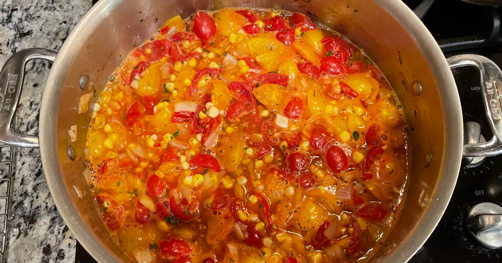 Ingredients for corn and tomato salsa from Ball Canning's recipe sitting in a stainless steel pot.