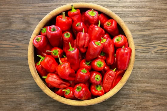 Wooden bowl full of red ripe paprika peppers.